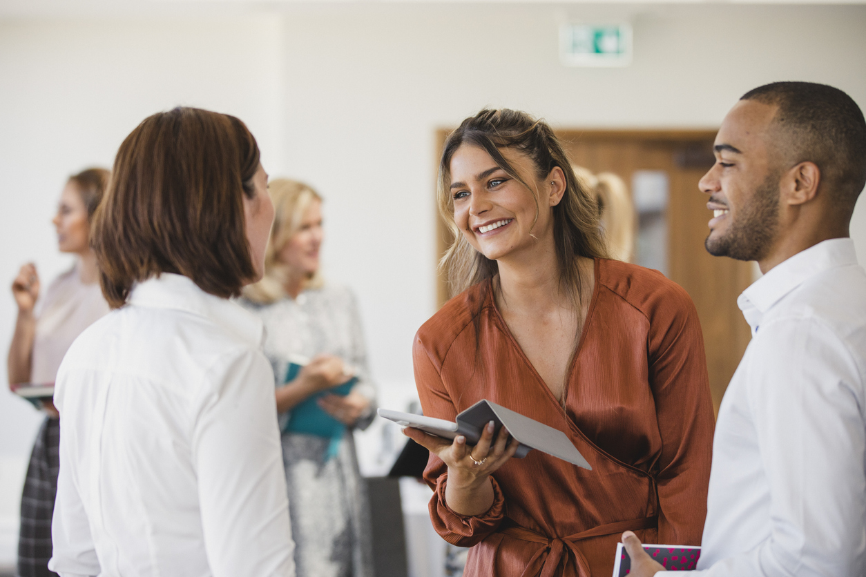 Cheerful young colleagues discussing with digital tablet