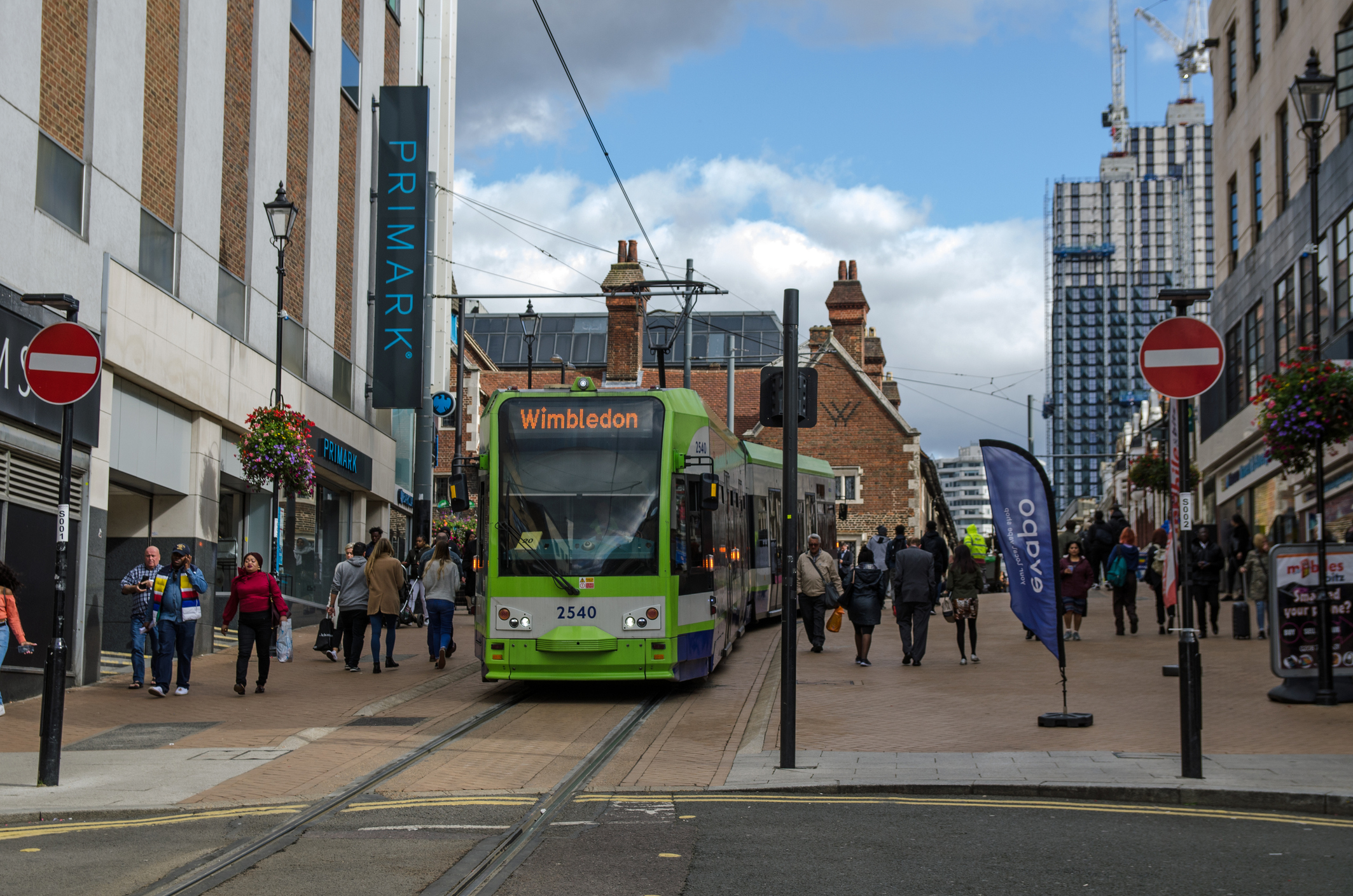 A tram travelling down a bustling street in Croydon, London