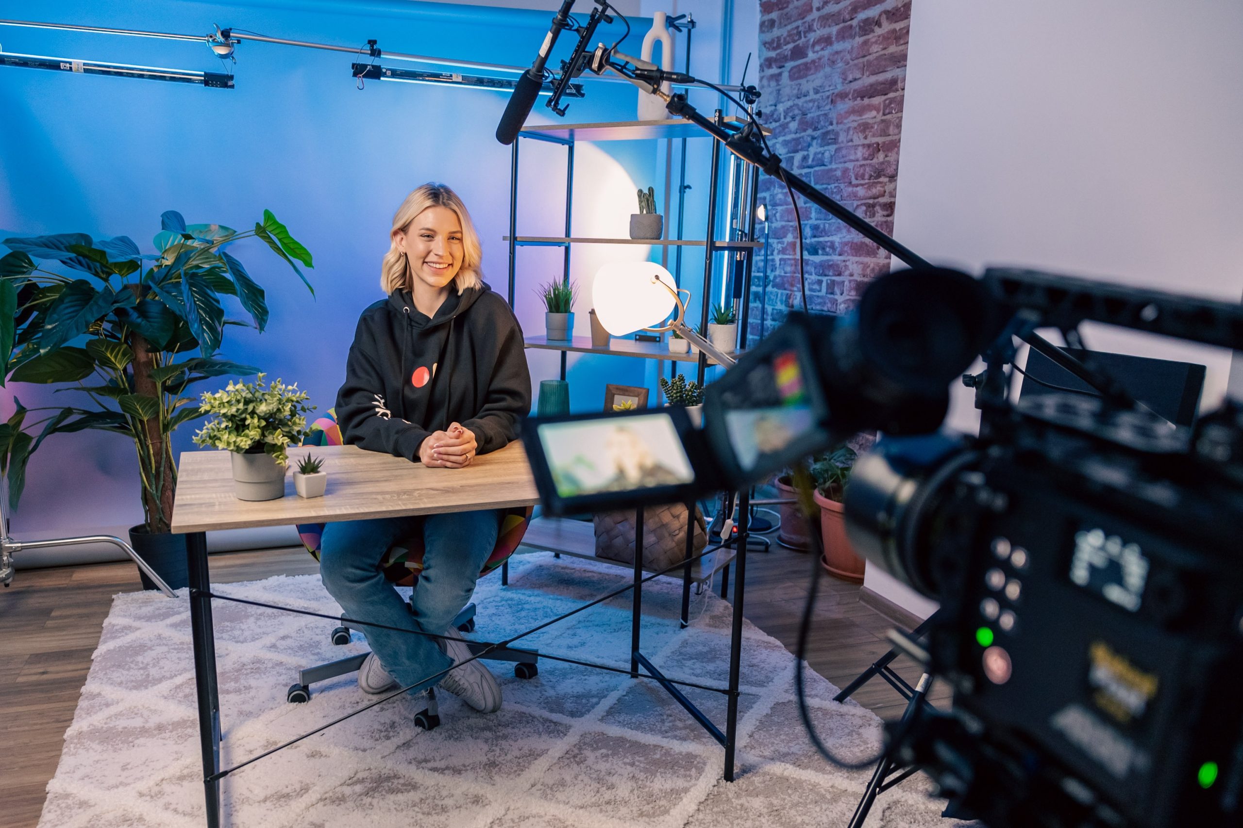 blonde-haired woman sitting at desk filming promotional video