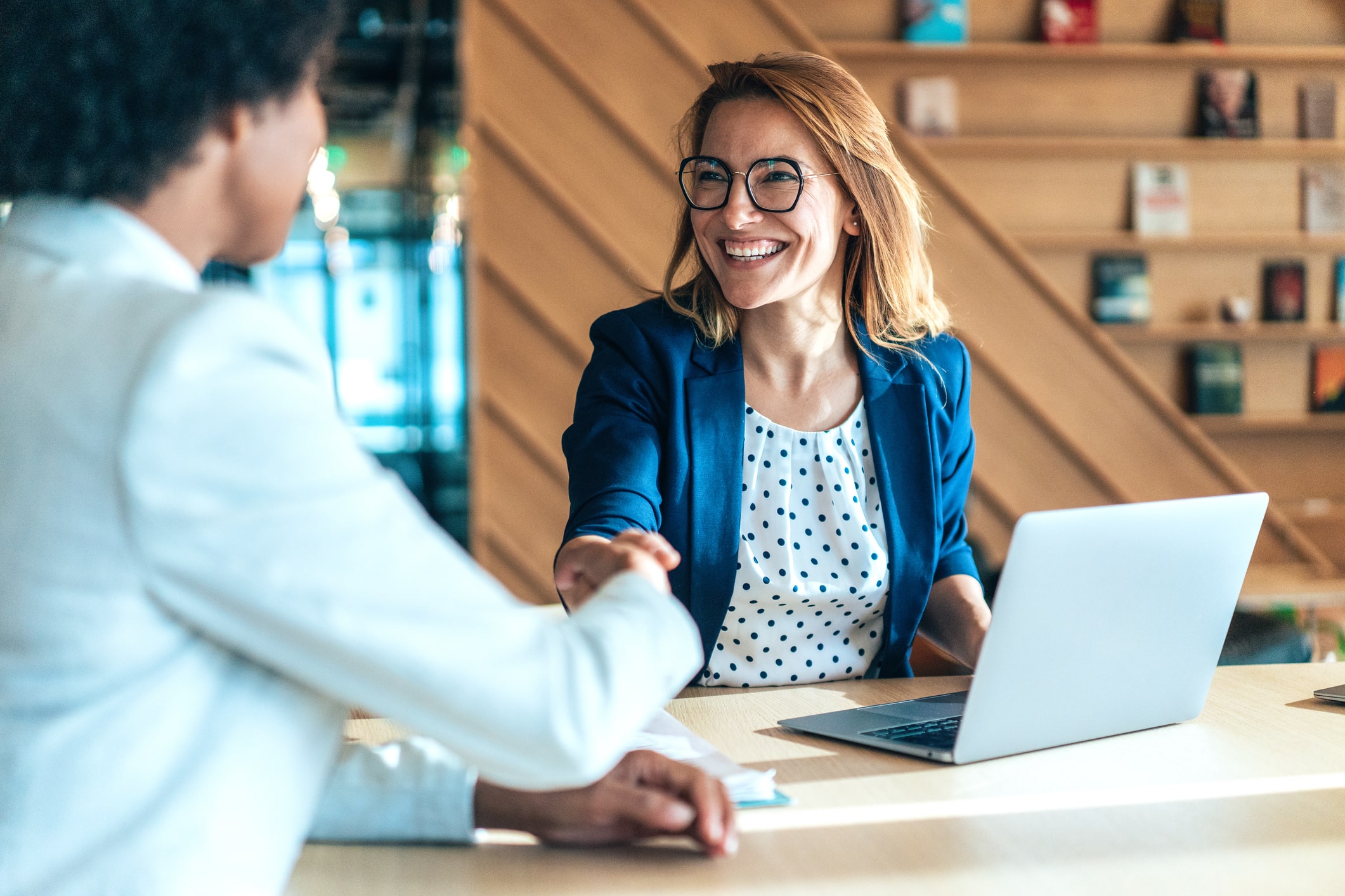 Two business people shaking hands and smiling at each other