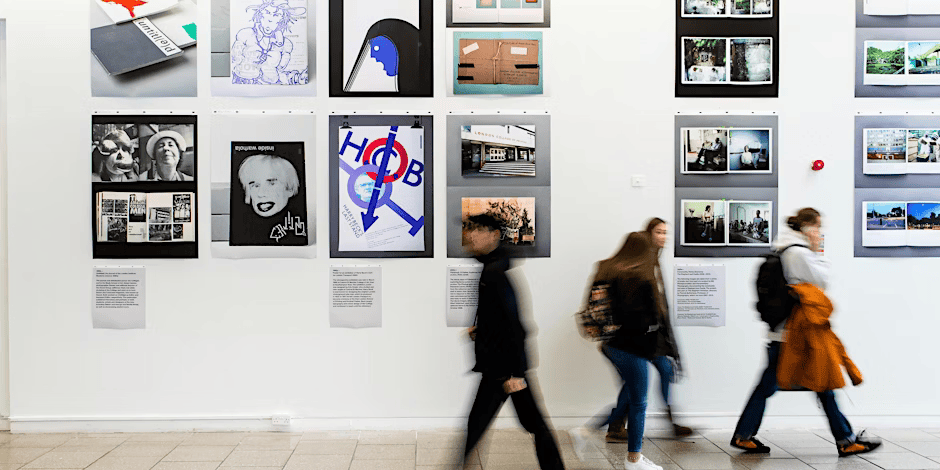 Group of people quickly walking past an art exhibition wall covered in posters and art